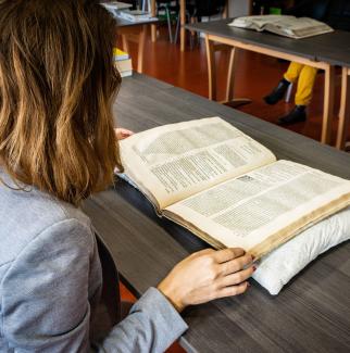 Une femme feuillette un livre du fonds ancien de la bibliothèque du centre de recherche Droit et sociétés religieuses